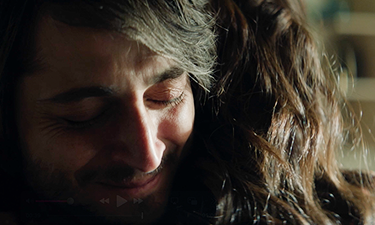 Man smiling emotionally while hugging a loved one, capturing a supportive moment in a mental health or caregiving context